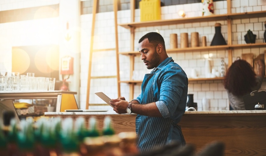 Shot of young man business owner working on a tablet in his coffee shop.