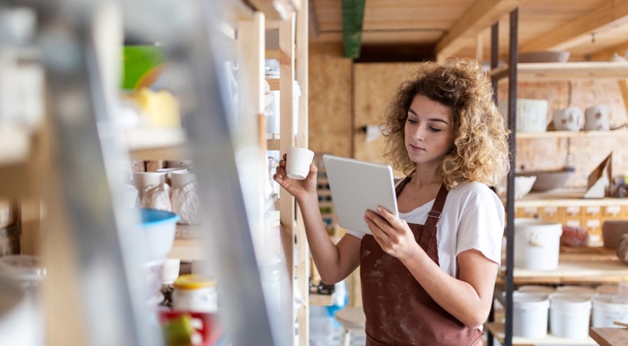Young woman working in an art studio with a tablet computer in her hand.