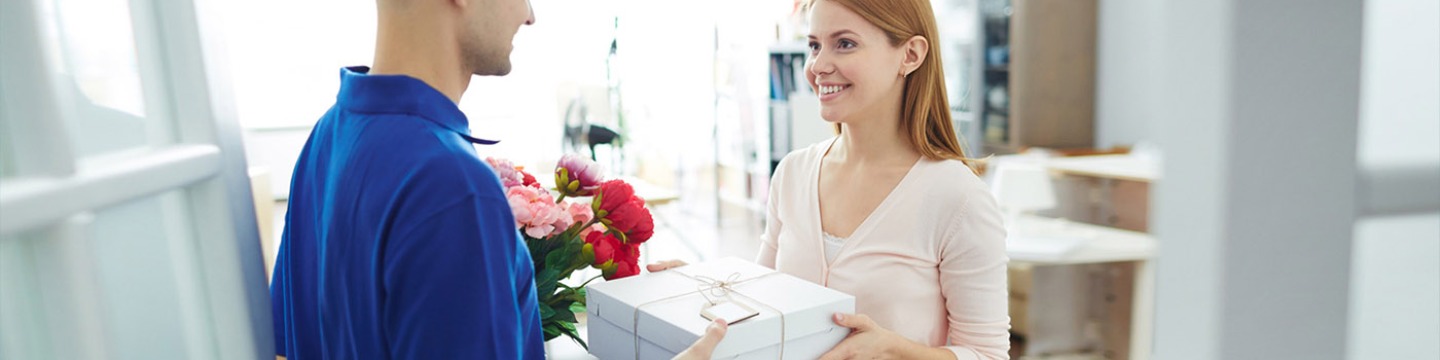 Woman receiving a parcel and flowers from a delivery service worker