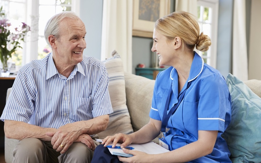 Female healthcare worker visiting a senior man at his home.