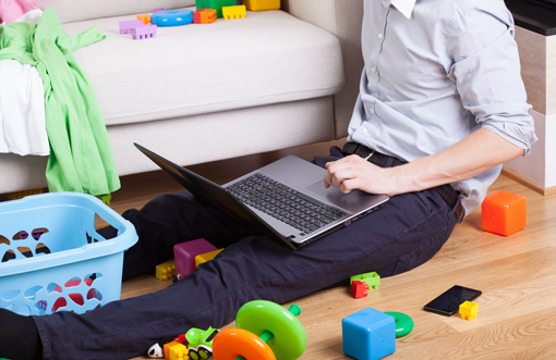 Man on laptop surrounded by children's toys