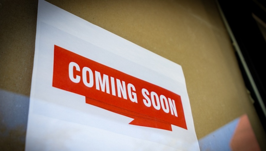 A "Coming Soon" sign posted in a building window.