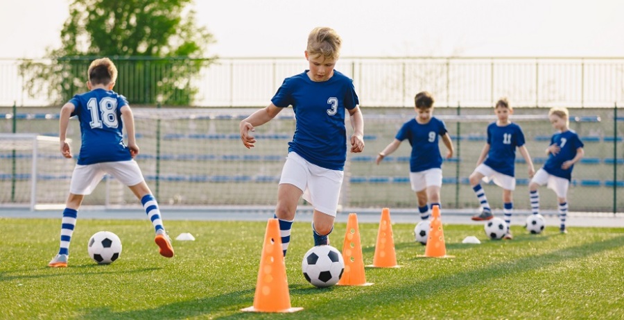 Group of boys doing soccer drills on a field.