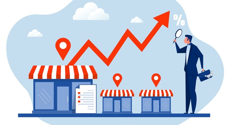 Franchise expansion concept with a businessman investor with magnifying glass looking at a rising line graph above three franchise locations.