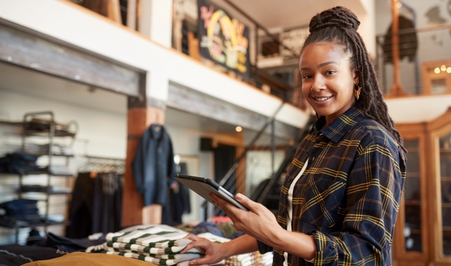 Female owner of clothing store using digital tablet to check stock.