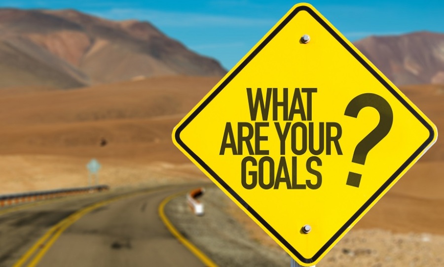 A "What Are Your Goals?" road sign in a desert highway setting.