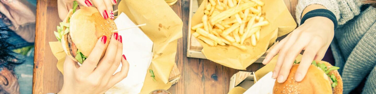 Personas comiendo unas hamburguesas con patatas