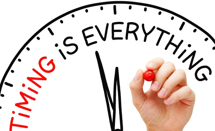 Hand writing "Timing is Everything" on a drawn clock with a red marker on a transparent wipe board.