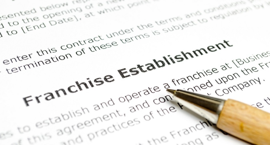 Legal document with the words "Franchise Establishment" bolded. There is a wooden pen lying on the paper.