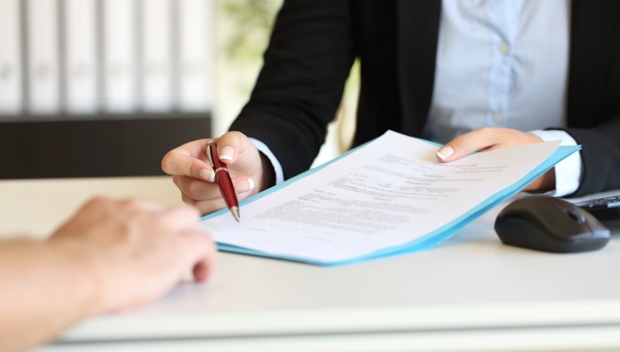 Close up of an executive hands holding a pen and indicating where to sign a contract.