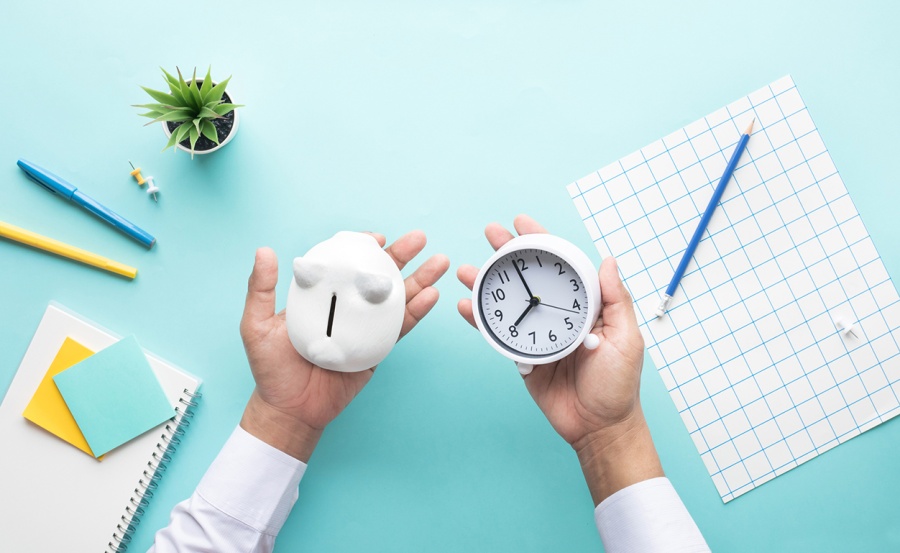 Hands holding a piggy bank and a clock