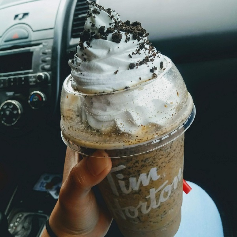 Picture of someone sitting in a car holding a Tim Horton’s classic Oreo cookies n’ cream iced cappuccino.