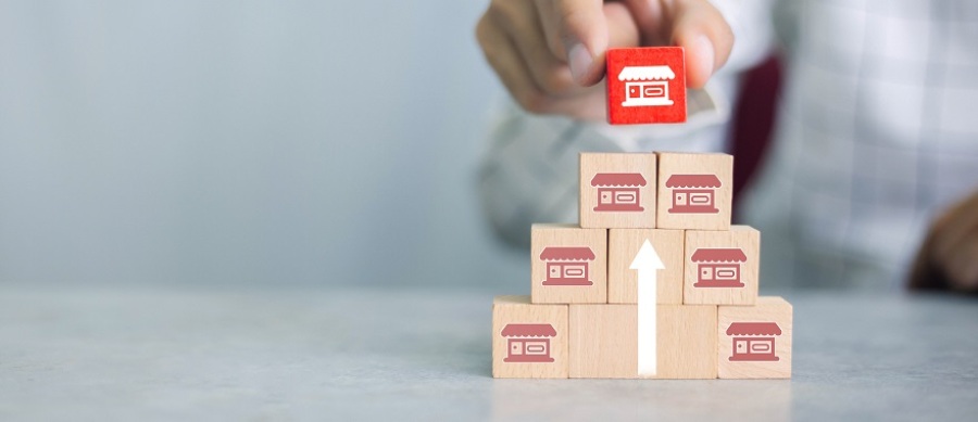 Businessman stacking wooden blocks with franchise icons on them.