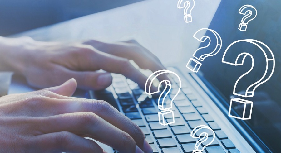 Person typing on laptop with question marks surrounding the keyboard.