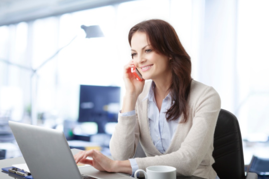 Woman on Laptop While Making Phone Call