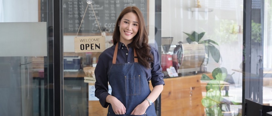 Female coffee shop owner standing at the door of her coffee shop.