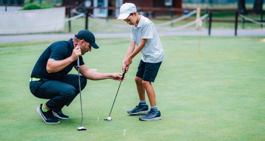 Boy practicing putting with an instructor.