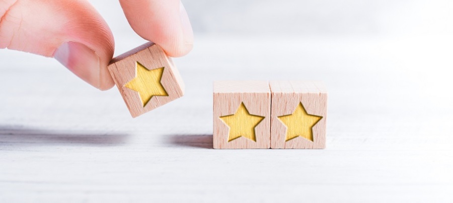 A hand arranging three blocks with gold stars on them.