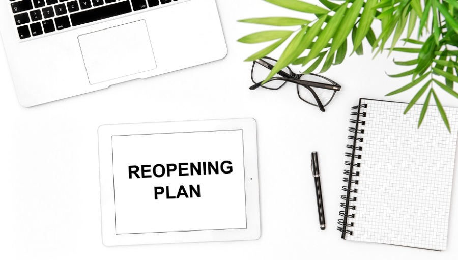 Tablet saying "reopening plan" on the screen on top of desk.